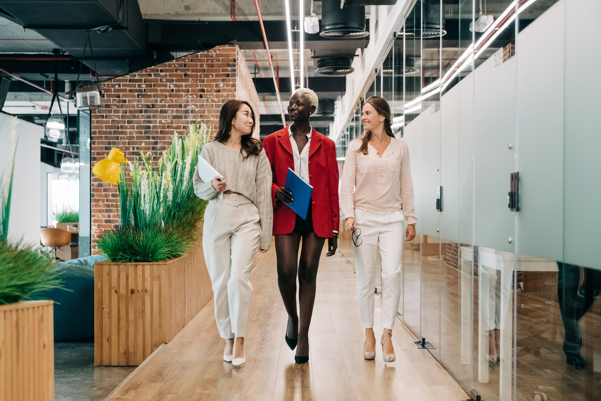 Diverse elegant multiracial businesswomen walking in contemporary office